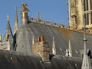 Vue rapprochée depuis le rooftop de l'Hôtel de la Cathédrale, montrant la statue équestre de Saint-Georges terrassant le dragon sur le faîtage du choeur, entourée de figurines d'angelots, ainsi que les demi-soleils et ornements dorés à la feuille d'or de la toiture de la cathédrale Notre-Dame de Rouen